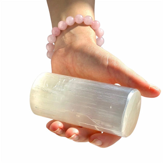 Selenite harmoniser crystal cylinder held in hand for energy healing