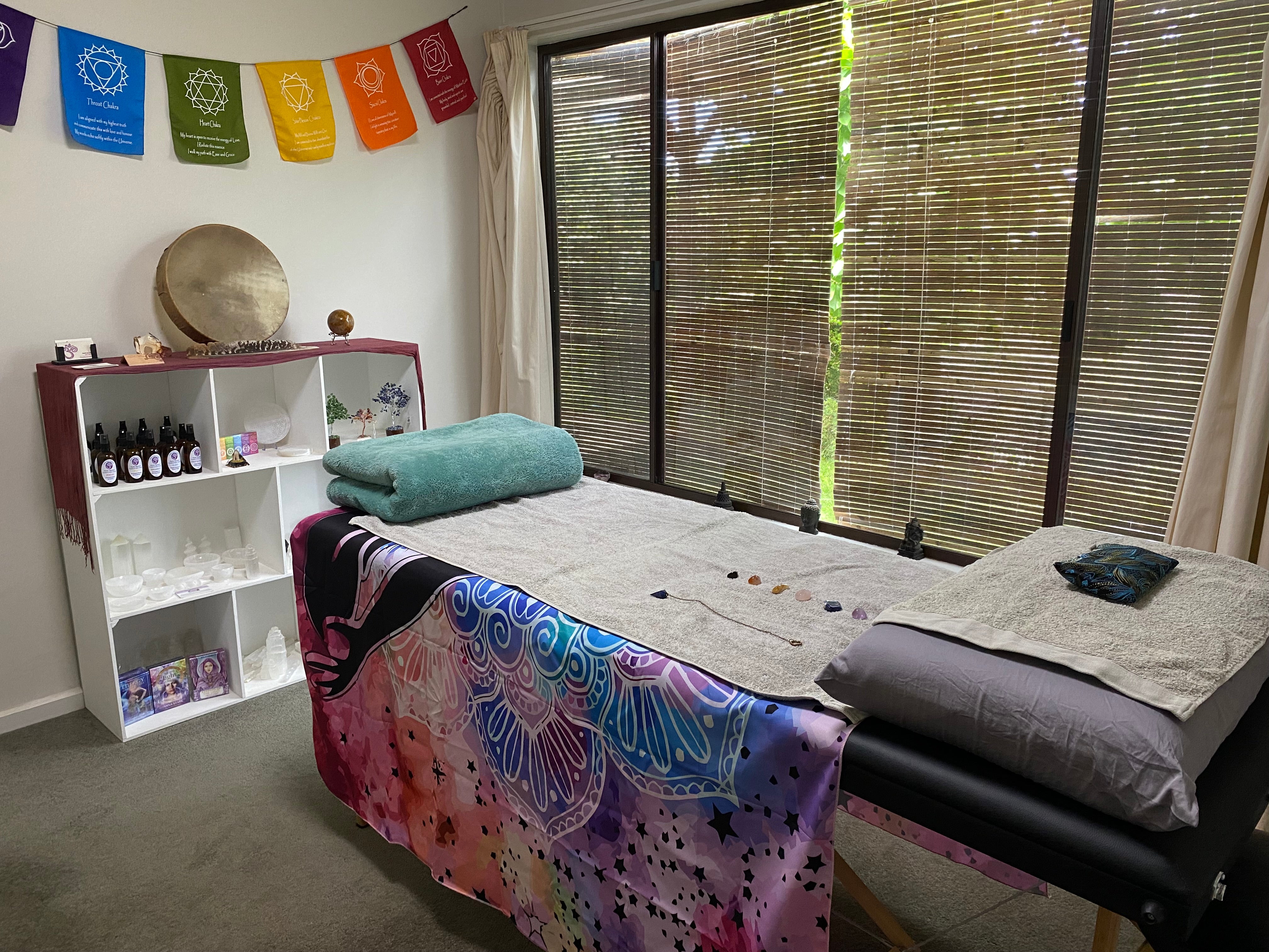 Reiki treatment room at Earth Aya Energy in Healesville, Yarra Valley — massage table with crystals, chakra flags, medicine drum, and healing products